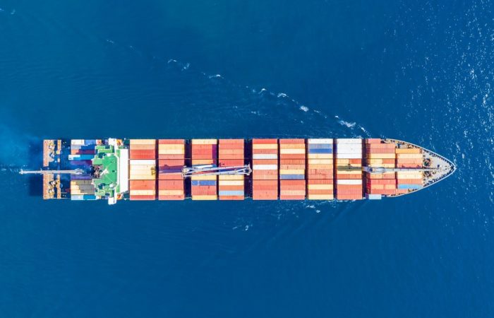 Cargo ship full loaded with containers, blue sea background, top view Cargo ship full loaded with containers, blue sea background, top view